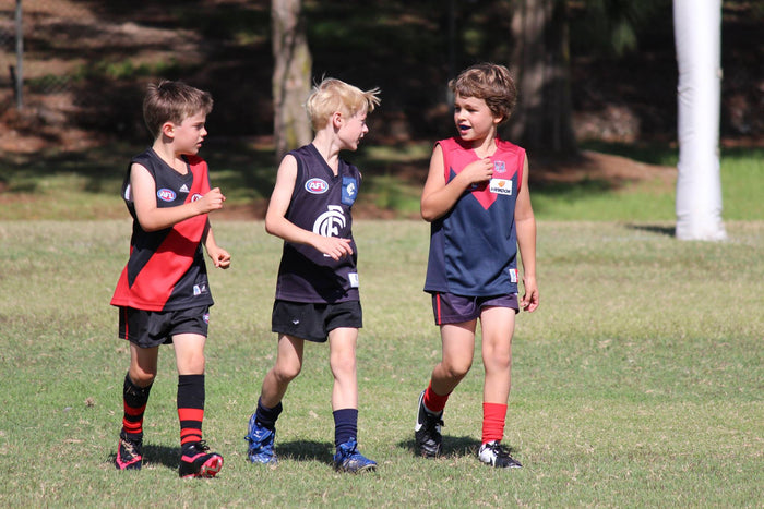 Three junior AFL players chatting at an ASC sports camp.
