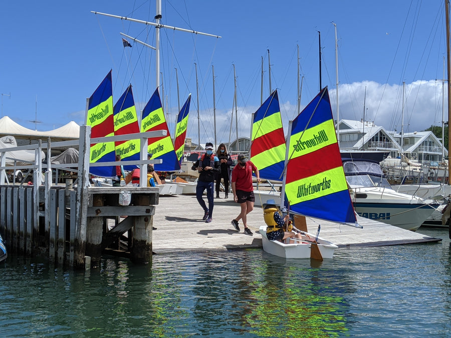 Launching dinghy's with colourful sails at an ASC sailing camp, with instructor and parents watching on