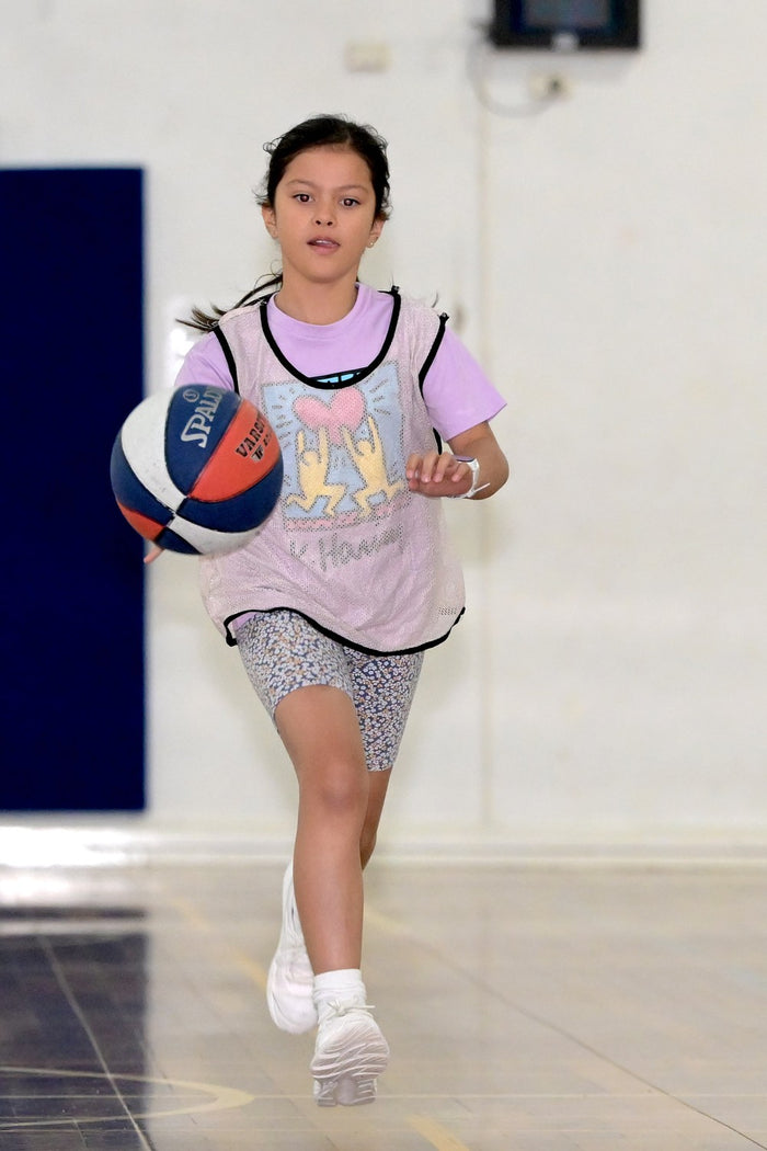 Young girl concentrating hard on perfecting her dribbling skills at an ASC basketball camp