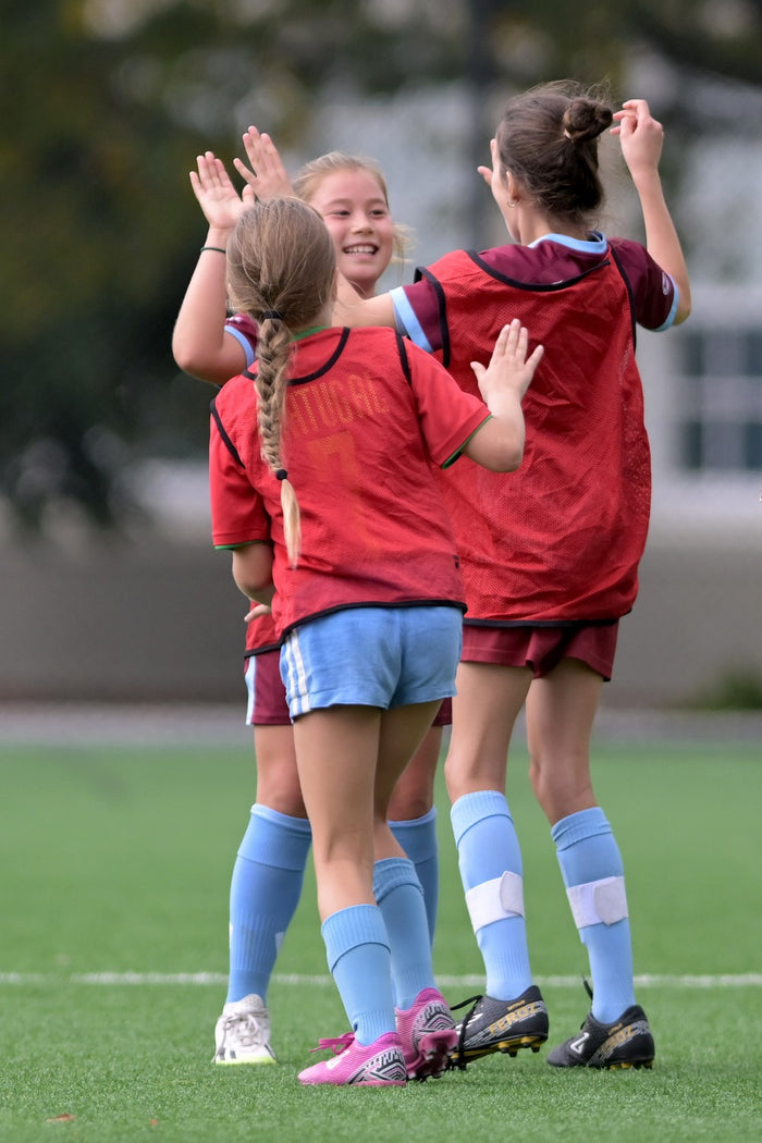Three young female soccer players congratulating each other after a great play at an ASC soccer camp