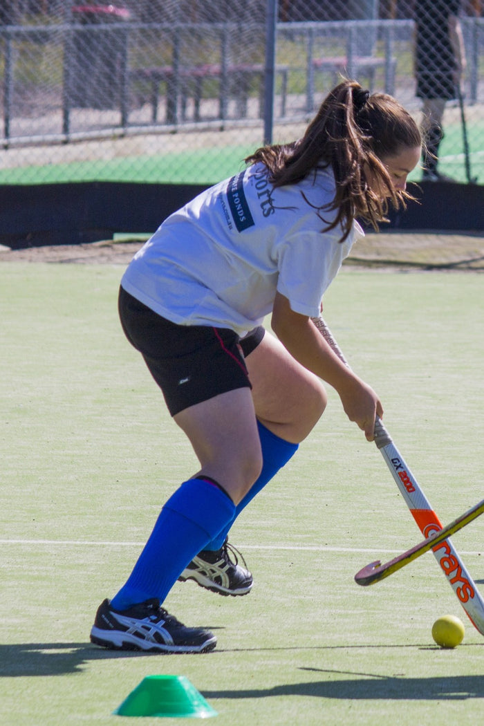 A teenage girl in a dual for the ball at an ASC hockey camp