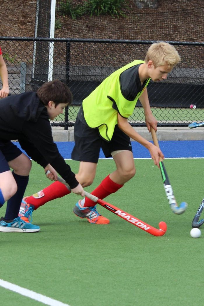 Young hockey players ompeting for the ball during match play at an ASC hockey camp