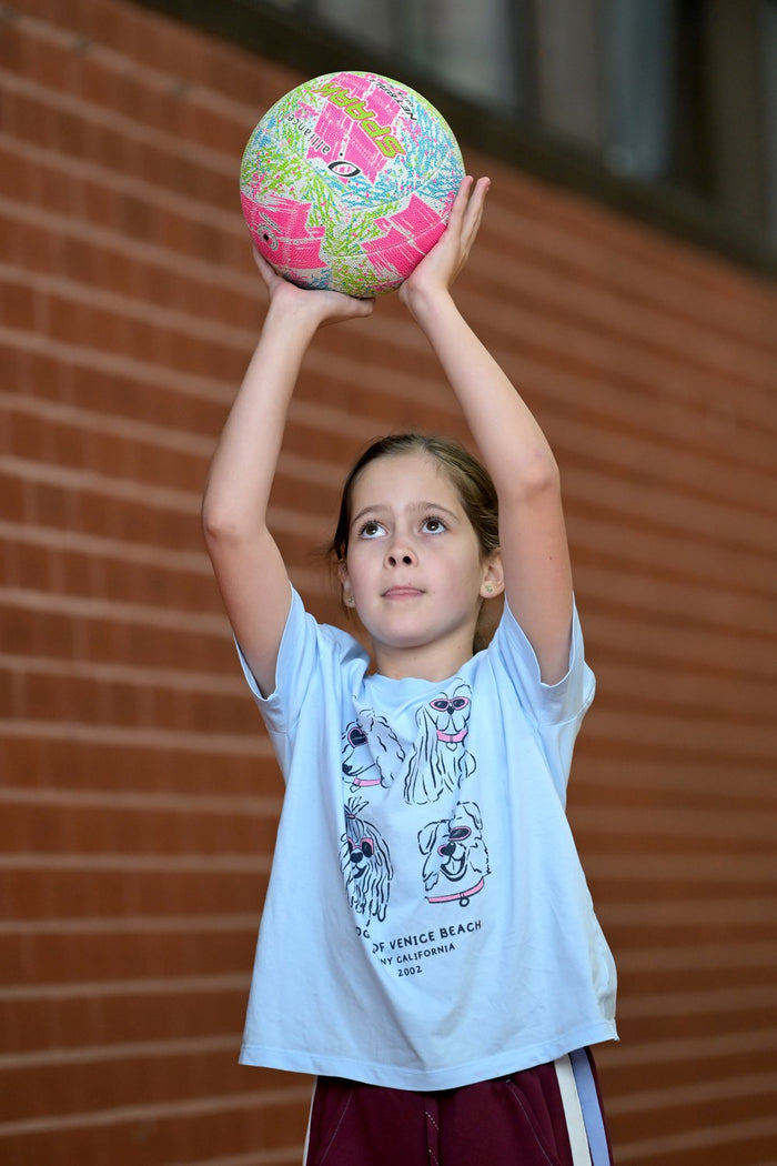 A young girl focusing very hard on making a coreect shot at an ASC netball camp