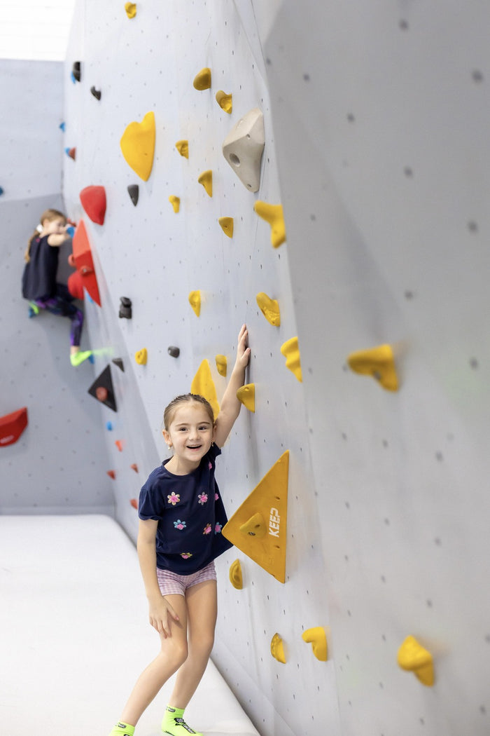 A young girl smiling after completing an indoor obstacle course at an ASC Nija Parc parkour skills program