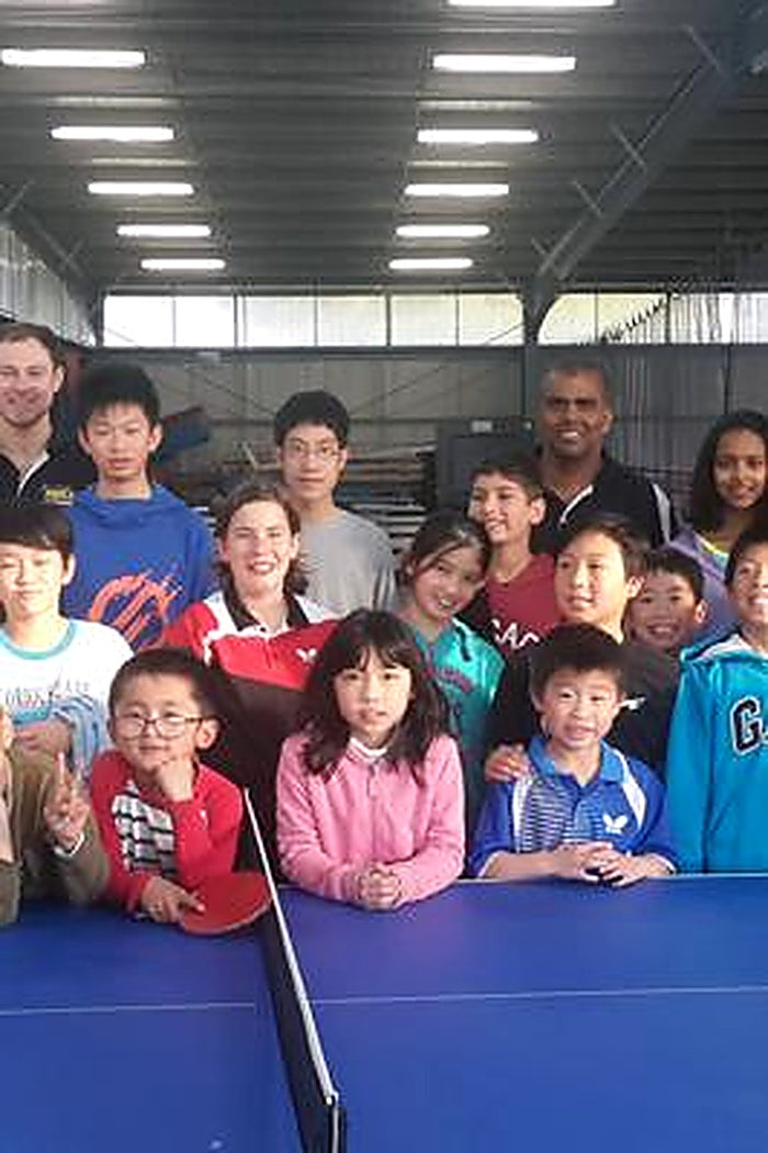 A group of children and coaches posing together at an ASC kids table tennis coaching program.