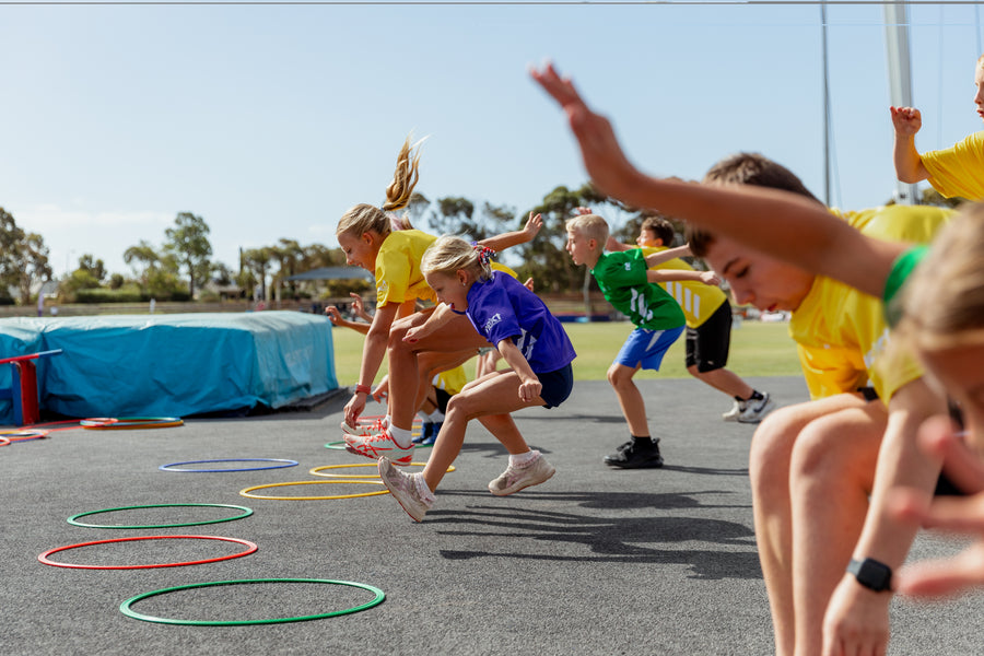 Children participating in a sports activity on a track with colorful hula hoops.