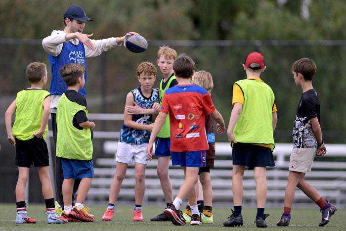 Children being coached in an AFL drill at an ASC sports camp