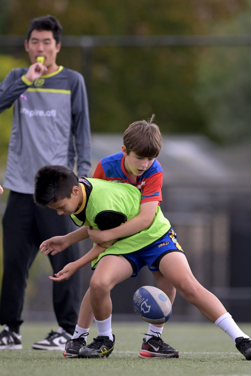 Coach watching two boys practising  tackling at an ASC AFL/AFLW camp