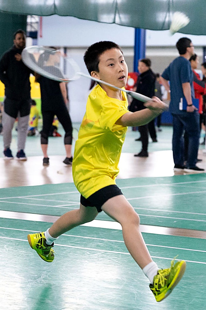 Young boy in full flight about to connect with the shuttlecock at an ASC badminton camp