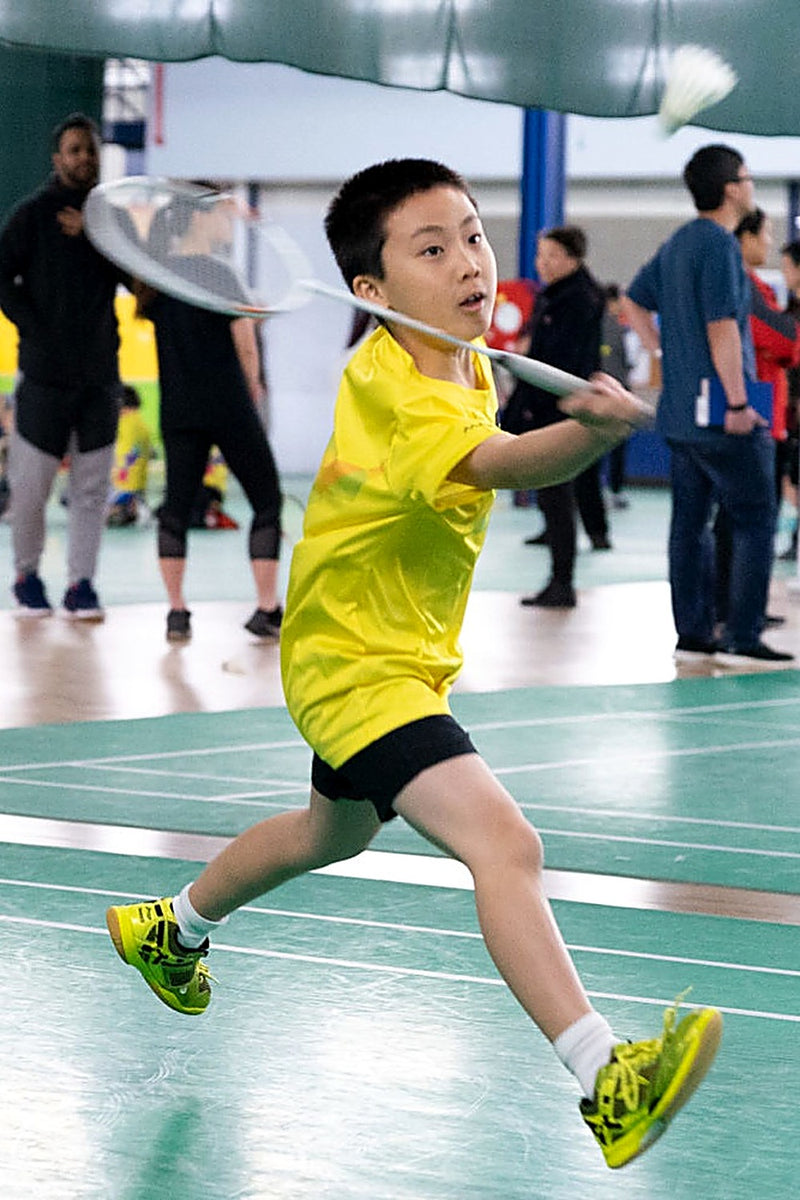 Young boy in full flight about to connect with the shuttlecock at an ASC badminton camp