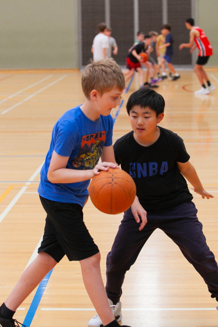 Two boys practising their dribbling contest skills at an ASC basketball camp
