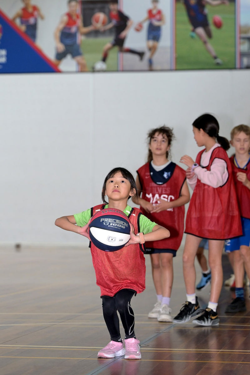 Young girl basketballer focusing on taking a shot during a training drill at an ASC basketball camp