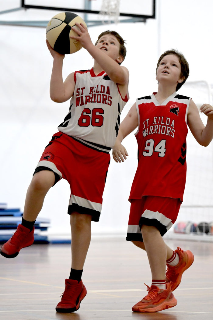 Two young boys at an ASC basketball camp. One going for the lay-up.