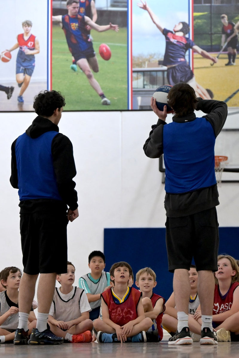 Group of young male participants listening to their coaches explaining a shooting drill