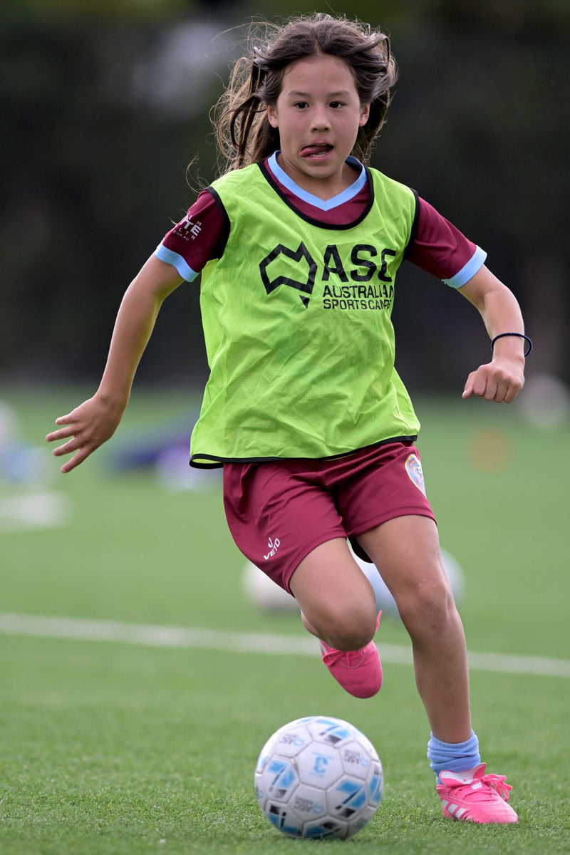 Young girl concentrating hard while doing a drill at an ASC soccer camp