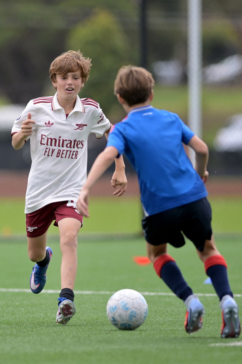 Two young soccer players one dribbling a soccer ball, one defending, during an ASC soccer camp