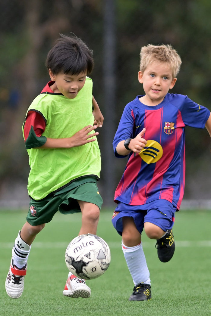 Two boys loving the chase for the ball at an ASC soccer camp
