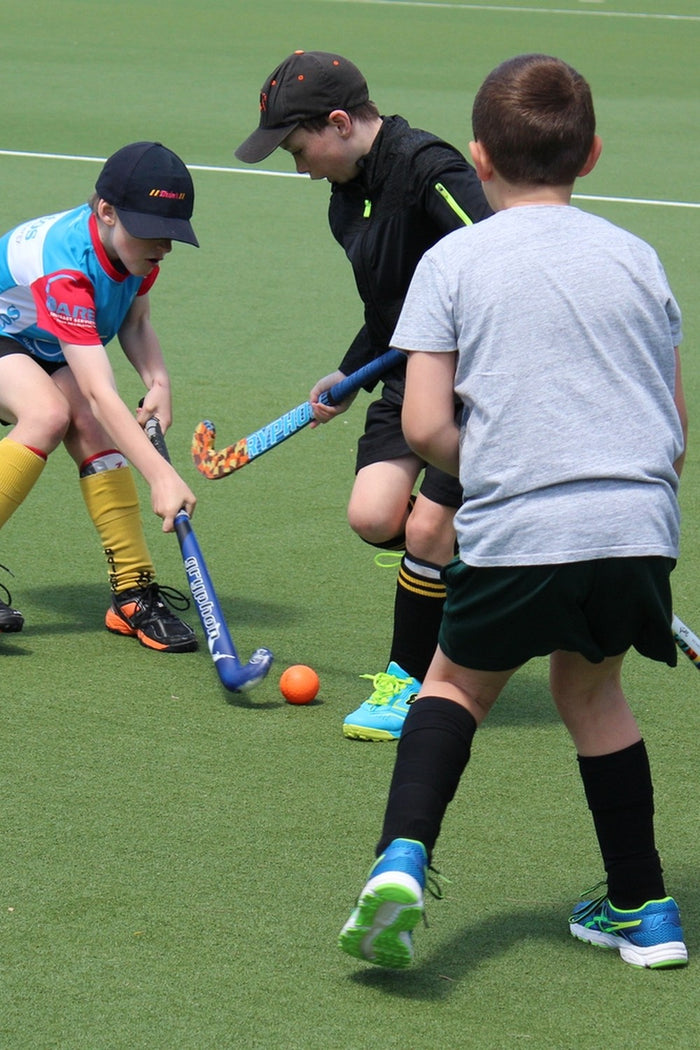 Young boys playing field hockey during an ASC hockey camp