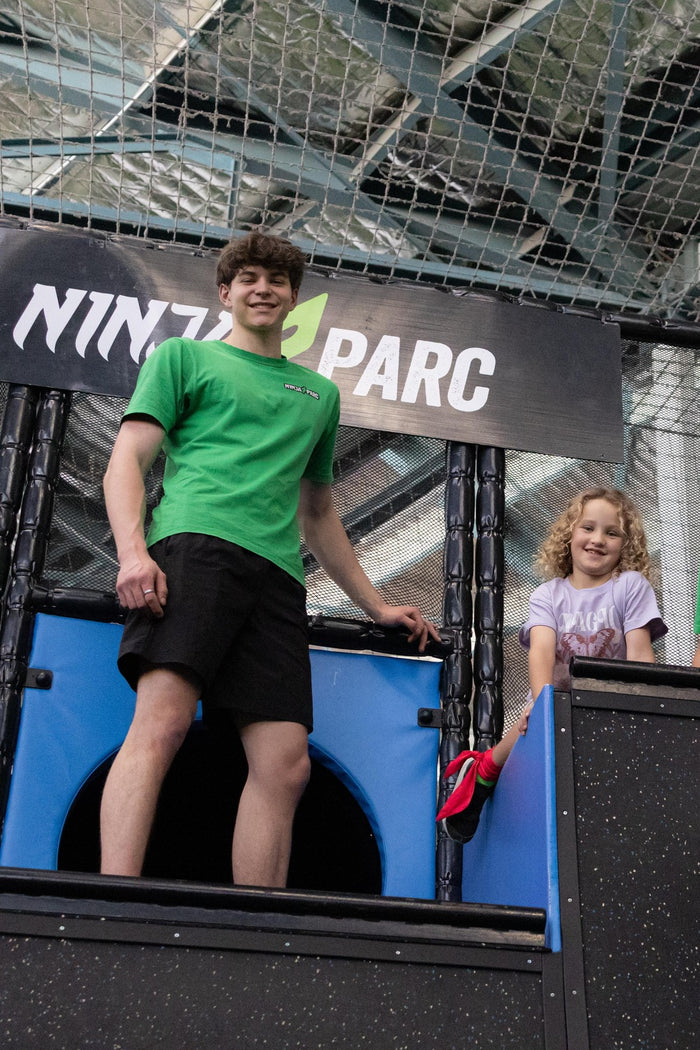 Coach and young girl on top of a large obstacle at an ASC parkour skills development program