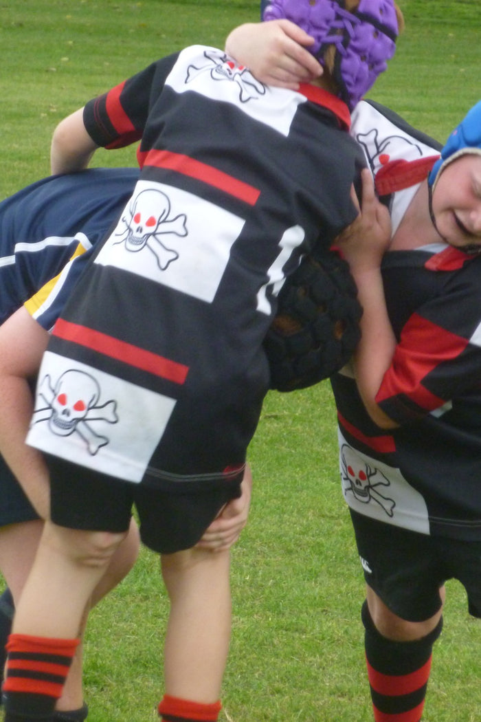 Three young rugby players in a tackle at an ASC rugby union camp.