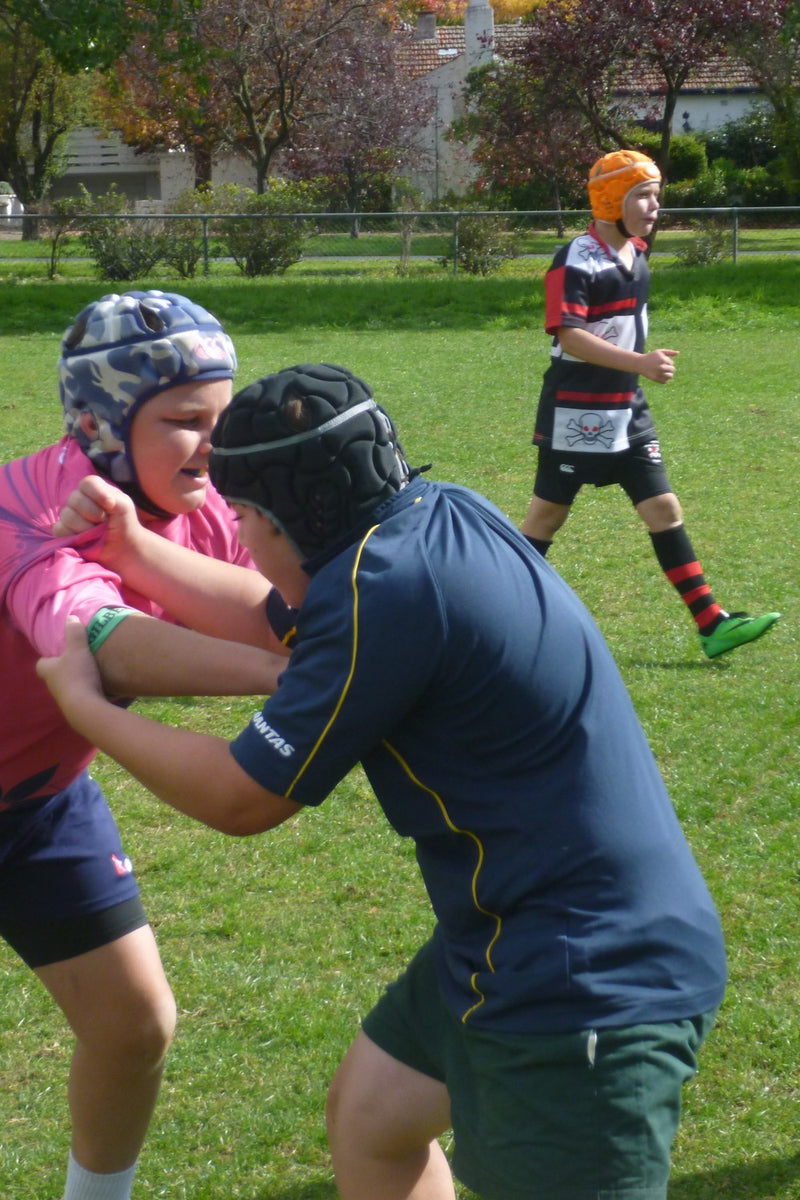 Youth rugby union forwards in protective headgear practising push and shove at an ASC rugby union camp.