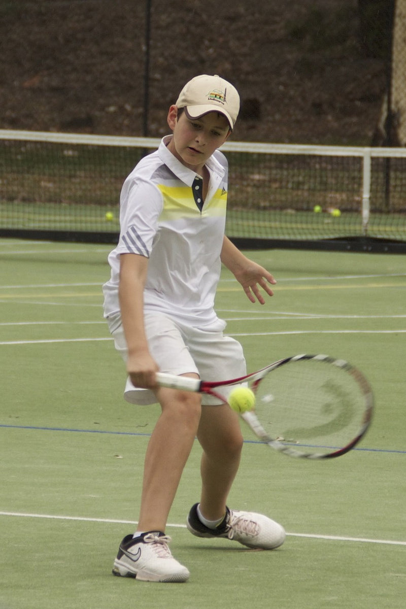 A young tennis player practising his cloe-up backhand at an ASC tennis camp.