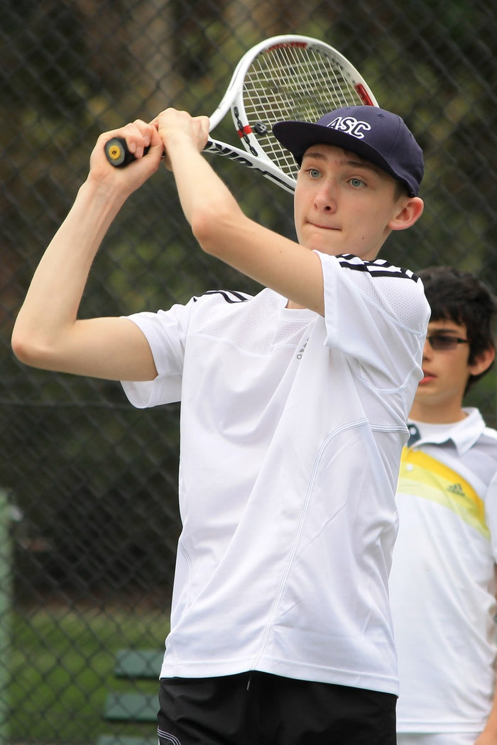 A young male tennis player practising a double handed-backhand at an ASC tennis camp