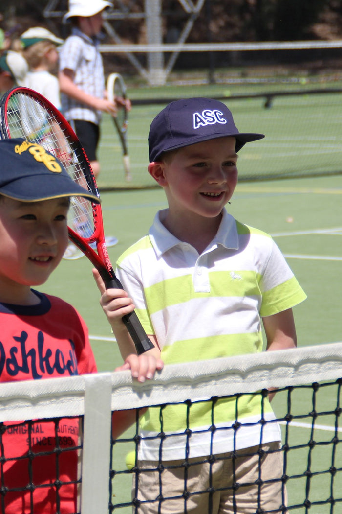 Two young boys at the net receiving tennis coaching at an ASC tennis camp
