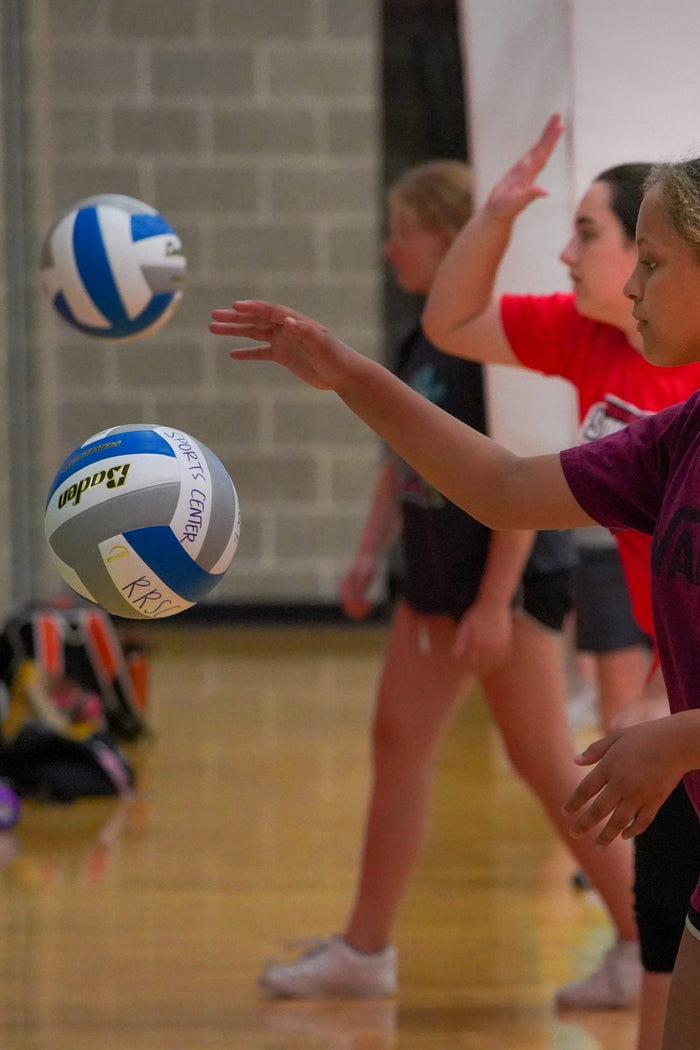 Young girls practising their volleyball sills against a wall at an ASC volleyball camp